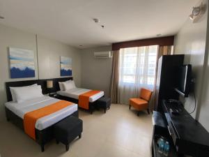 um quarto de hotel com duas camas e uma televisão de ecrã plano em Holiday Suites em Puerto Princesa