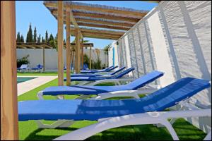 a row of blue and white lounge chairs on the grass at Bungalow La Roa V in Conil de la Frontera