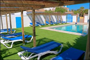 a group of lounge chairs and a swimming pool at Bungalow La Roa V in Conil de la Frontera
