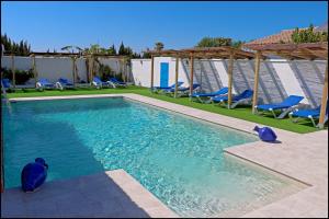 a swimming pool with blue chairs and chairs in a yard at Bungalow La Roa V in Conil de la Frontera +24 photos