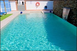 a swimming pool with blue water in a building at Bungalow La Roa IV in Conil de la Frontera