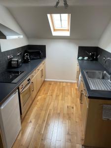a kitchen with black counter tops and a wooden floor at The Apartment at St Georges Terrace in Cheltenham