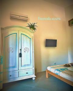 1 dormitorio con armario azul y TV en B&B Le pavoncelle sarde, en Flumini di Quartu
