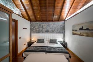 una camera con due letti e un muro di pietra di CASA RURAL EL LAGAR TENERIFE a La Orotava