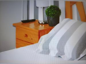 Una cama con sábanas blancas, un tocador y una planta en Hostal Cervantes, en Daganzo de Arriba