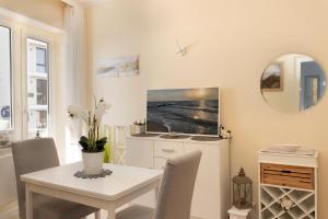 ein weißes Esszimmer mit einem Tisch und einem Spiegel in der Unterkunft Solymar Strandgeschichten in Grömitz