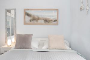ein weißes Schlafzimmer mit einem Bett mit weißen Kissen in der Unterkunft Solymar Strandgeschichten in Grömitz
