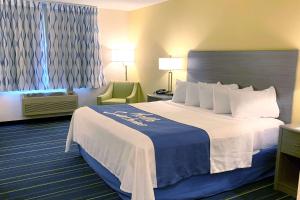 a hotel room with a large bed and a chair at Days Inn by Wyndham Hinckley in Hinckley