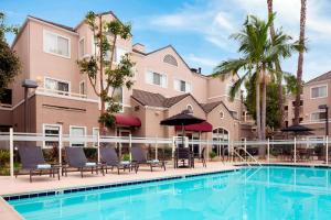 una piscina con sillas y sombrillas frente a un edificio en Sonesta ES Suites Carmel Mountain - San Diego, en San Diego