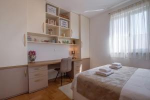 a bedroom with a bed and a desk and a window at SEA VIEW- spacious apartment with shared pool in Split