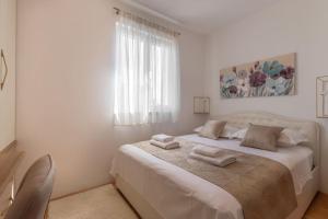 a white bedroom with a bed with two towels on it at SEA VIEW- spacious apartment with shared pool in Split