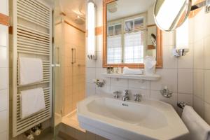 a white bathroom with a sink and a mirror at Hotel & Restaurant Alte Rheinmühle in Busingen am Hochrhein