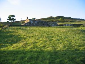 a large grassy field with a house on a hill at Rake Hey Farm in Todmorden