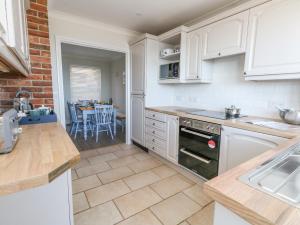 a kitchen with white cabinets and a dining room with a table at Castle Cove Cottage in Weymouth