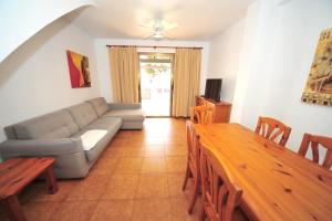ein Wohnzimmer mit einem Sofa und einem Tisch in der Unterkunft Orange Park Duplex Familiar Jardin in Benicàssim