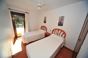 1 Schlafzimmer mit 2 Betten, einem Fenster und einem Ventilator in der Unterkunft Orange Park Duplex Familiar Jardin in Benicàssim