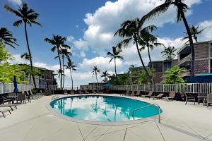 una gran piscina con sillas y palmeras en Alii Villas 201, en Kailua-Kona