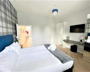 een slaapkamer met een groot wit bed en een televisie bij Luxury Reno'd 1 Bed Nr Bruntsfield & The Meadows in Edinburgh
