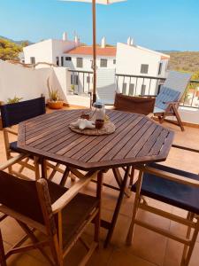 einen Holztisch auf einer Terrasse mit Stühlen und einem Sonnenschirm in der Unterkunft Gin&Tonic Apartment in Son Parc