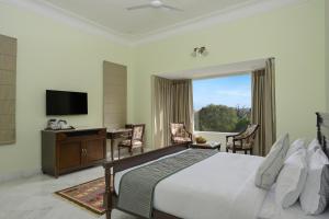 a bedroom with a bed and a desk and a television at Boheda Manor - Luxury Retreat in Udaipur