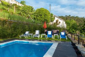 una piscina con sillas y sombrillas junto a una casa en Quinta das Pedras Novas, en Covas