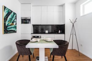 a white kitchen with a table and two chairs at Akácfa 413 Luxury AirCon Center Apartment in Budapest