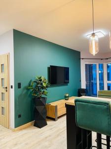 a living room with a green wall with a tv at APARTAMENT ELEGANCE GREEN w Let's Sea Basen&SPA in Gąski
