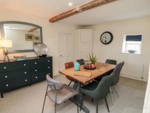 a dining room with a table and chairs and a clock at Black Horse Cottage in Northallerton