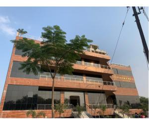 a tall building with a tree in front of it at Hotel Padmawati Grand in Nānded