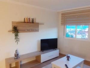 a living room with a flat screen tv and a table at APTO. SANXURXO in Camariñas