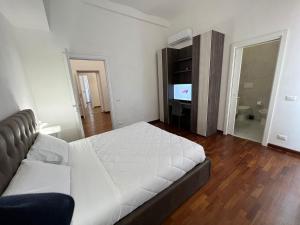 Schlafzimmer mit einem weißen Bett und einem TV in der Unterkunft StarHome Colosseo in Rom