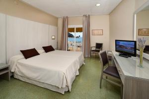 a bedroom with a bed and a desk with a television at Hotel Capri in Tossa de Mar