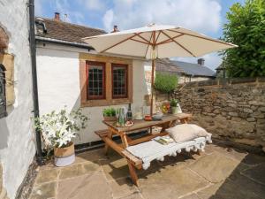 uma mesa de madeira com um guarda-chuva num pátio em Hope Cottage em Bakewell