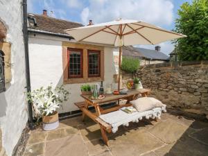 a wooden table with an umbrella on a patio at Hope Cottage in Bakewell