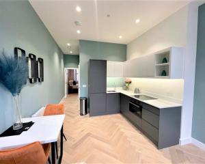 a kitchen with white counters and orange chairs at Trendy and Newly Reno'd 1 Bed Nr The Meadows in Edinburgh