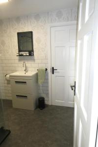 łazienka z umywalką i telewizorem na ścianie w obiekcie Cheerful cottage between the mountains and the sea in West Wales w mieście Penuwch