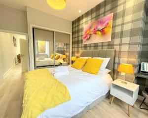 um quarto com uma cama grande e almofadas amarelas em Chic, Newly Reno'd 1 Bed Open Plan, nr The Meadows em Edimburgo
