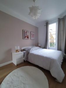een slaapkamer met een wit bed en een raam bij Logement entier:Asnières sur Seine (10mn de Paris) in Asnières-sur-Seine