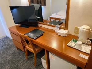 a desk with a computer and a television on it at Blue Port Hotel Kitakyushu Airport in Kanda