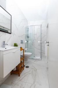 uma casa de banho branca com uma cabina de duche em vidro e um lavatório. em Mouzinho 129 - Medronheiro & Oliveira no Porto