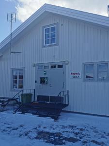 a white building with a door and a sign on it at Fjällägenhet boende Huså Byskola in Huså