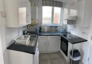 a small kitchen with white cabinets and a sink at Seabreeze in Lyme Regis