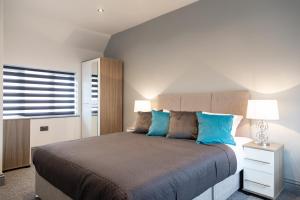 a bedroom with a large bed with blue pillows at Central location ideal for contractors, families and business travellers in Ashford