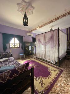 1 dormitorio con paredes moradas, 1 cama y ventana en Dar Ilyana, en Aït Tiourhza