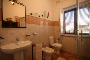 a bathroom with a sink and a toilet and a mirror at Azzurra ideale per famiglie in Donoratico +8 photos
