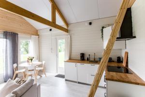 uma cozinha e sala de jantar com uma escada numa pequena casa em Chalet met loft - vakantiepark de Schreiershoek em Dokkum