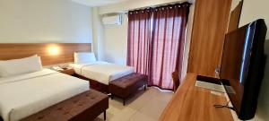 Cette chambre comprend 2 lits et une télévision à écran plat. dans l'établissement Mango Suites, à Tuguegarao