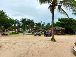 a palm tree on the beach with people on motorcycles at Pousada da praça in Jericoacoara