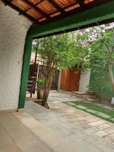 a building with a green wall and a patio with trees at Casa em São Pedro da Aldeia in São Pedro da Aldeia