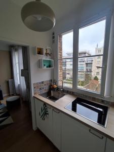 une cuisine avec un évier et une grande fenêtre dans l'établissement Logement entier:Asnières sur Seine (10mn de Paris), à Asnières-sur-Seine